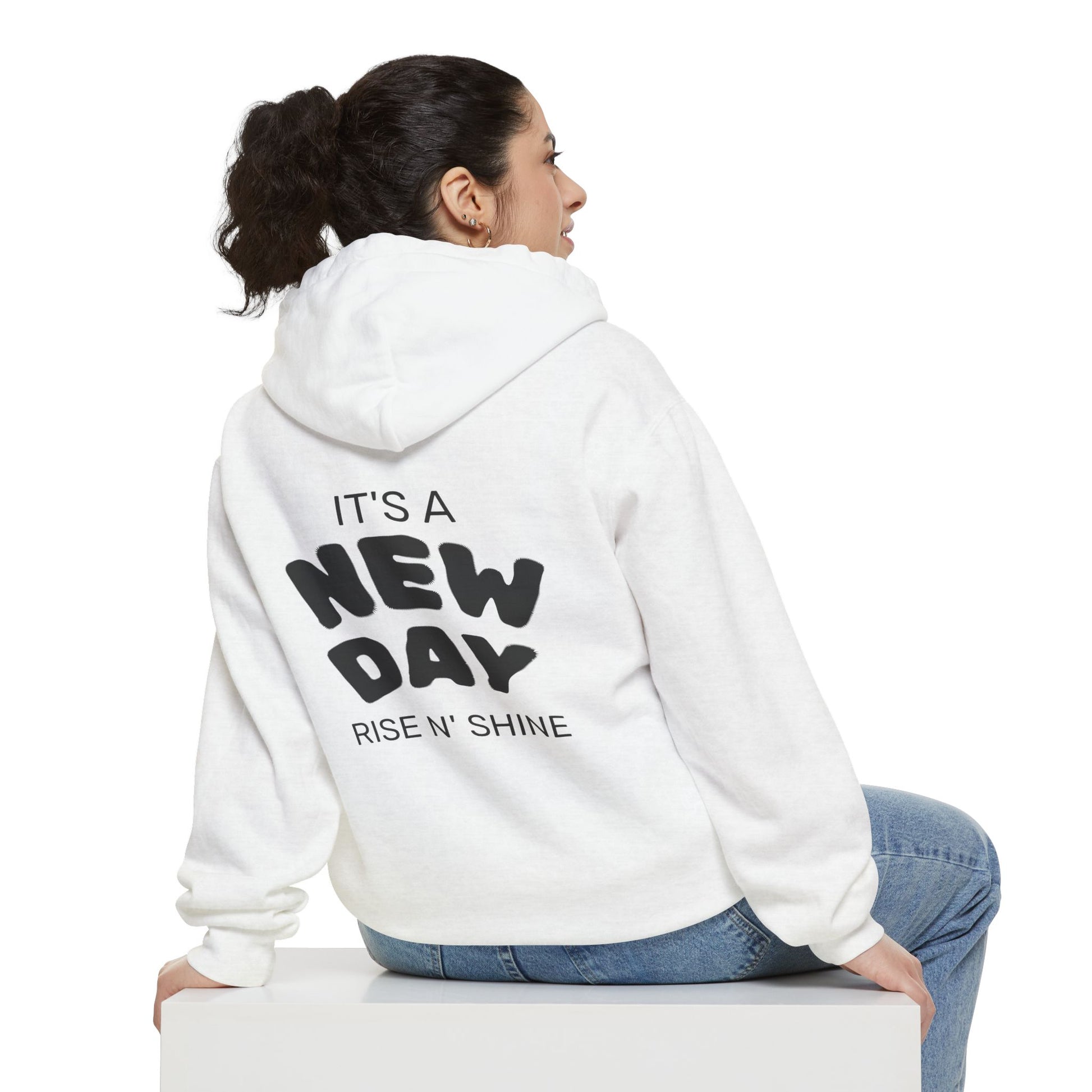 Person wearing a white hoodie with text on the back, sitting on a white surface.