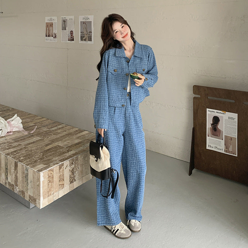 Person wearing a blue checkered outfit in a room with a wooden table and wall art.